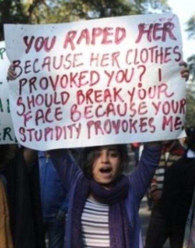 Young woman holding a sign saying 'You RAPED her because her clothes provoked you? I should break your face because your stupidity provokes me.'